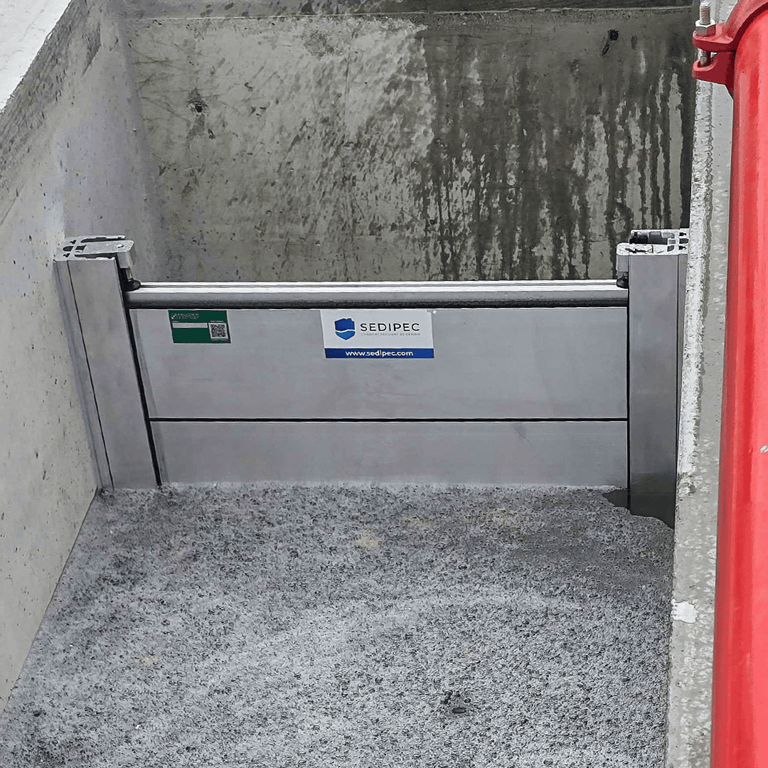 Passage en béton brut barré par un batardeau CASTOR+ de deux palplanches en aluminium entre deux poteaux latéraux
