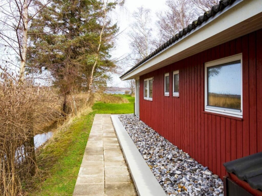 Maison en bois longée par une bande de gravier sous laquelle le FloodFrame est enterré