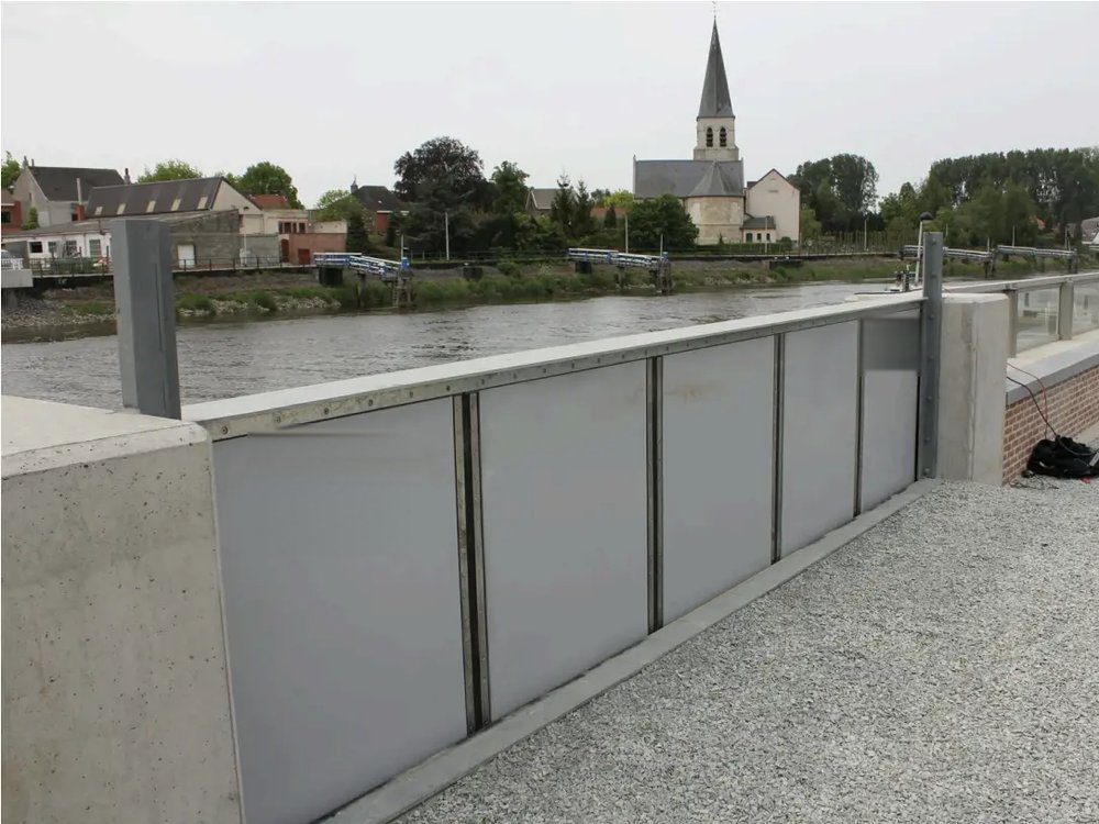 Barrière anti-inondation montée en travers d'un quai, le long d'une rivière