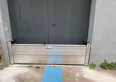 Barrière anti-inondation installée devant une porte industrielle