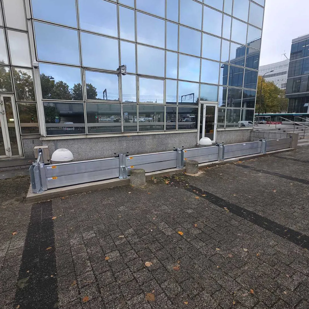 Batardeaux aluminium démontables posés au pied de la façade vitrée d'un bâtiment public, avec poteaux intermédiaires