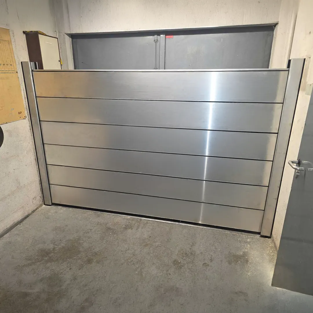 Batardeau en aluminium à lames horizontales fermant le bas d'une porte intérieure, entre deux montants