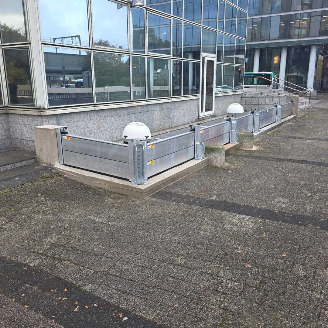 Plusieurs travées de batardeaux aluminium alignées au pied d'une façade vitrée de bâtiment public