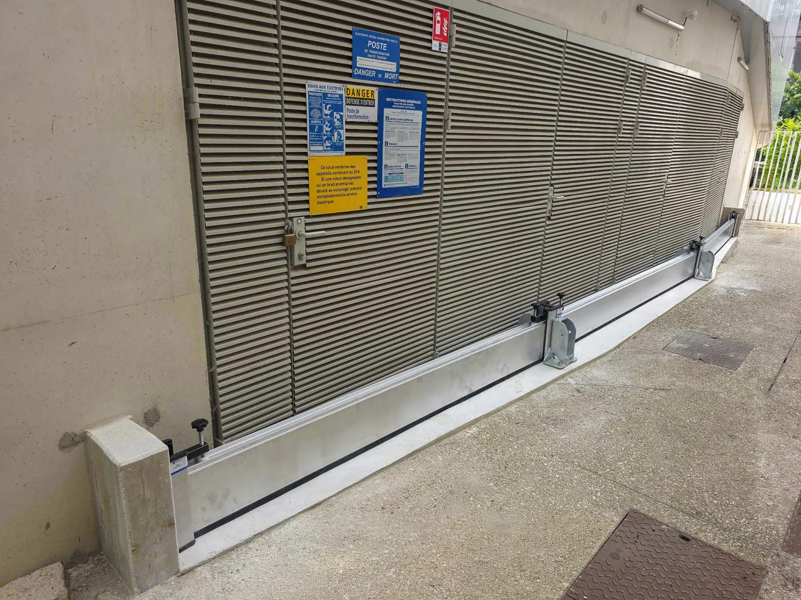 Batardeau aluminium posé au pied de la grille de ventilation d'un poste de transformation électrique