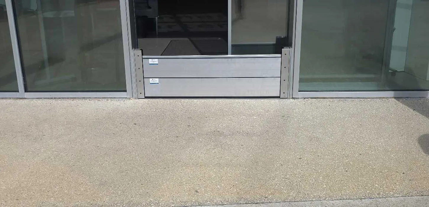 Batardeau aluminium à lames fermant le bas d'une entrée vitrée