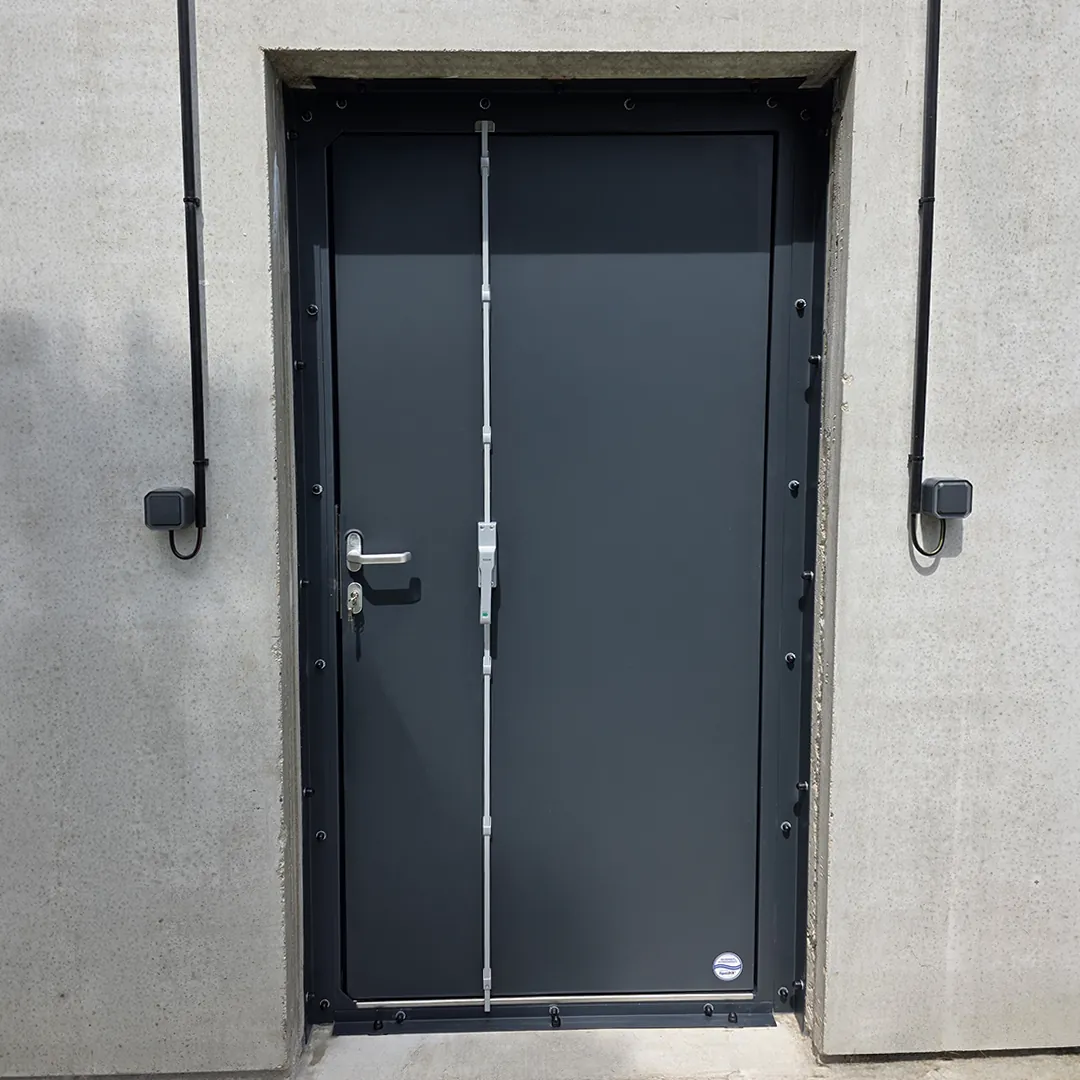 Porte anti-inondation anthracite à fermeture verticale, cadre fixé dans un mur en béton