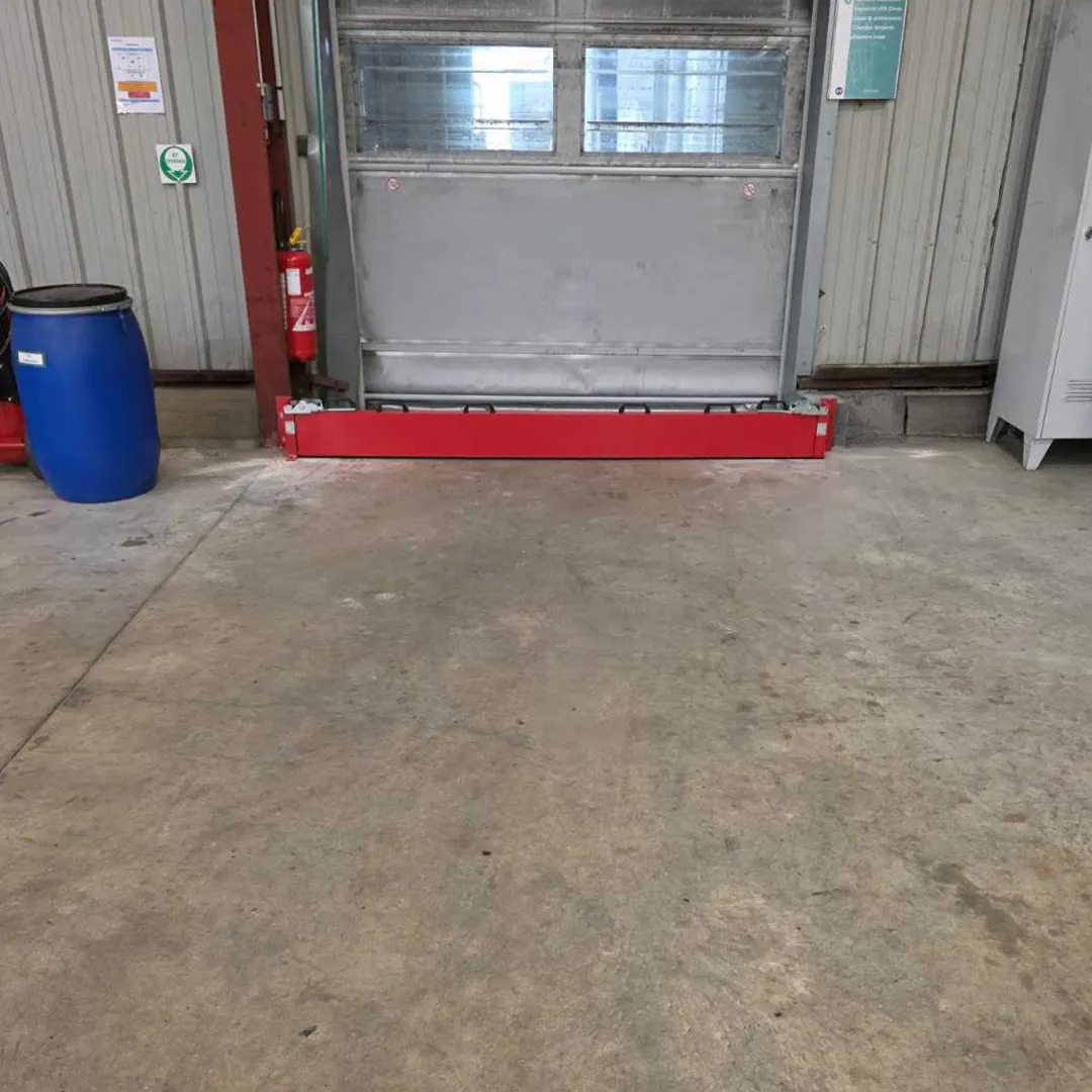 Barrière de rétention rouge posée au pied d'une porte dans un local de stockage